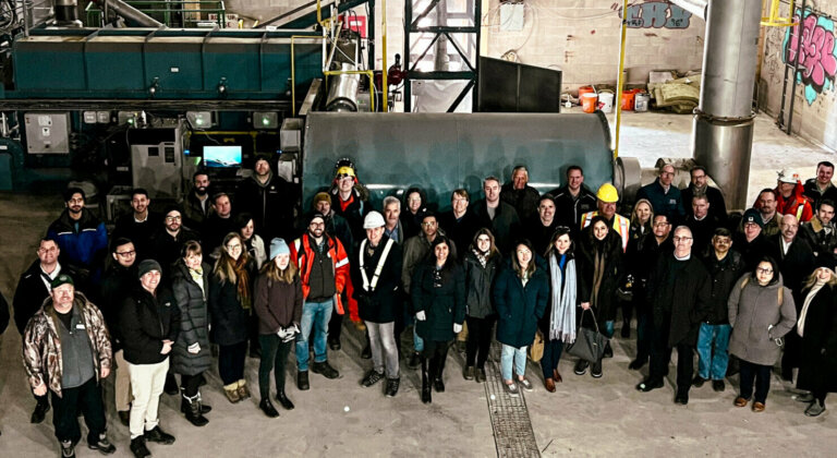 Group of people standing in front of machinery at a biochar production facility